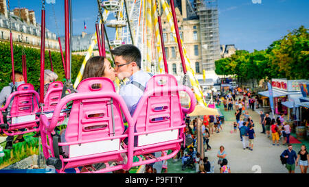 Un beau couple asiatique s'embrasse sur les chaises oscillantes de la Fete des Tuileries à Paris, France Banque D'Images