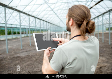 Agriculteur avec le comprimé dans la serre Banque D'Images