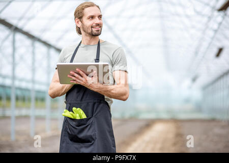 Agriculteur avec le comprimé dans la serre Banque D'Images