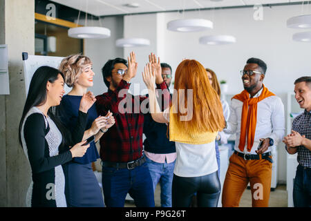 Hindo guy and Caucasian woman with red hair sont offrant un rapport de cinq à l'autre avec deux hads parmi leurs amis. Bonne réunion Banque D'Images