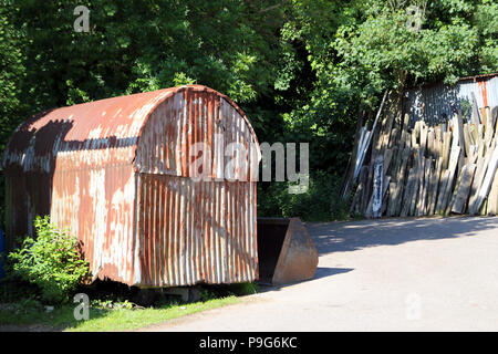 Tomber en ruine d'un ancien bâtiment de ferme en tôle ondulée avec vieux bois plancher bois à l'arrière-plan, sur une journée ensoleillée avec des arbres Banque D'Images