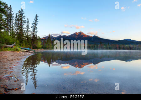 Golden sunrise éclate sur la montagne Pyramid et faible brouillard s'installe sur la surface d'Edith Lake dans le Parc National Jasper avec des reflets sur son calme Banque D'Images