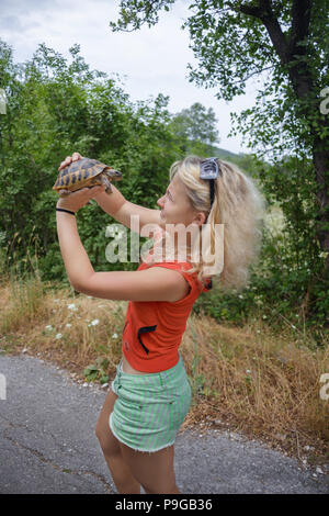 Fille tenir la tortue sur la route Banque D'Images