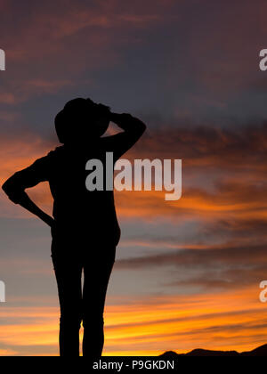 Femme en pantalon avec chapeau à la silhouette au coucher du soleil, le lever du soleil. Avec fond copyspace. Banque D'Images