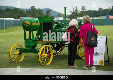 2 femmes lire signer sur & historique vue tracteur vert et jaune du kérosène (Waterloo Boy) stationné au RHS Flower Show de Chatsworth, Derbyshire, Angleterre, Royaume-Uni. Banque D'Images