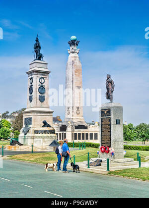 8 juin 2018 : Plymouth, Devon UK - Couple avec deux chiens à la recherche de monuments à Plymouth Hoe - de gauche à droite, l'Armada Monument, la Royal Navy Monum Banque D'Images