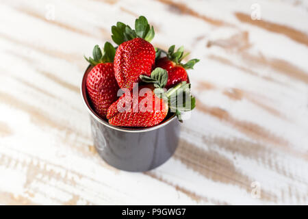 Dans une tasse de fraises rouge sur blanc, de bois. Alimentation saine. Banque D'Images