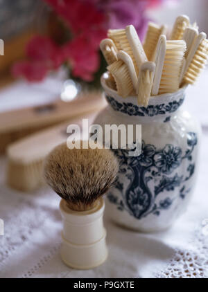 Close-up of a vintage cheveux du blaireau Blaireau à côté d'un pot bleu et blanc ivoire vintage avec des brosses à dents adossés Banque D'Images