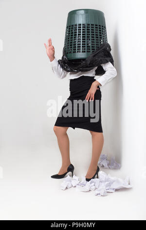 Fille avec corbeille sur la tête indique OK signe. Dorky femme standning par danser avec la benne d'ordures sur la tête. Isolé sur fond blanc. Banque D'Images