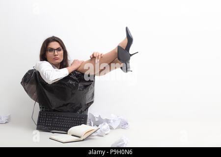 Agacé businesswoman sitting in poubelle. Assistant de bureau femelle avec regard de colère sur son visage se trouve dans la corbeille avec ordinateur portable Clavier et certains Banque D'Images