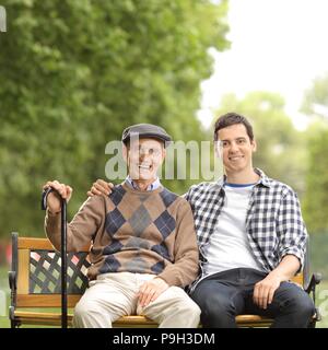 Un homme âgé et un jeune homme assis sur un banc à l'extérieur Banque D'Images