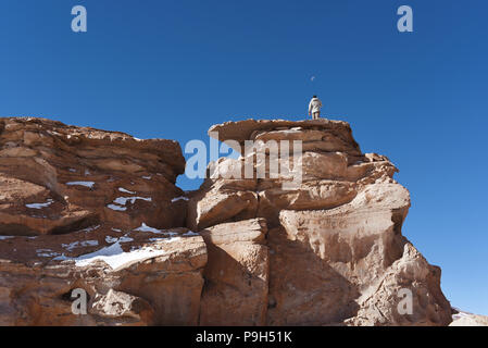 L'homme au sommet d'une montagne de roche regarder la lune à l'Arbora de Piedra (arbre de Pierre) au sein de la faune andine Eduardo Avaroa, Réserve nationale de la Bolivie. Banque D'Images