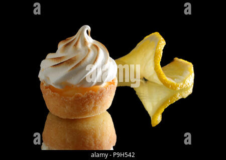 Mini tartelettes au citron meringuée sur un fond réfléchissant noir Banque D'Images