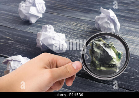 Un dollar froissé sur une table à côté des boules de papier blanc. Le processus de réflexion et de trouver de nouvelles idées d'affaires, des solutions rentables. De l'attraction en Banque D'Images