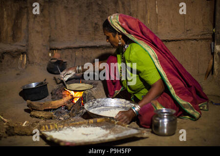 Une femme faisant chantais sur un feu ouvert dans sa cuisine, Sendhwa, Inde. Banque D'Images