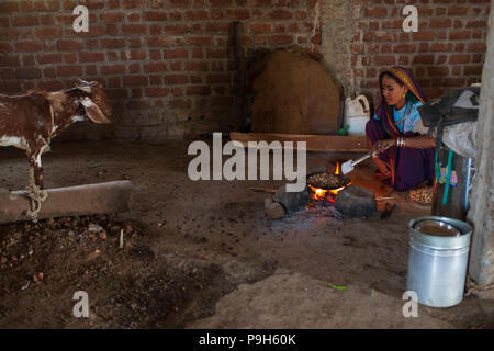 Une femme arachides grillées sur un feu ouvert à leur domicile en milieu rural, l'Inde Sendhwa. Banque D'Images