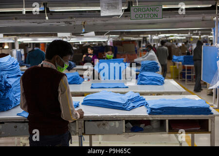 Un homme T-shirts de pliage sur une ligne de production d'une usine de vêtements, où le coton biologique est utilisé pour faire des vêtements, Indore, Inde. Banque D'Images