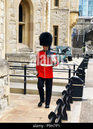 Un membre de la garde de la reine des marches et se distingue à la sentinelle de la Tour de Londres à Londres, en Angleterre. Banque D'Images