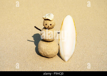 Sandman joyeuse surfer avec une planche de surf sur le sable. Noël et nouvel an concept sur une plage tropicale. Des couleurs vives. concept de surf. sandy snowman dans un c Banque D'Images