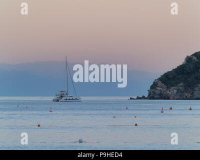 Spotorno, Bergeggi Italie June 15,2018 : catamaran voilier ancré à côté de petite île vue de Spotorno plage, montagnes silohuette en backgroun Banque D'Images