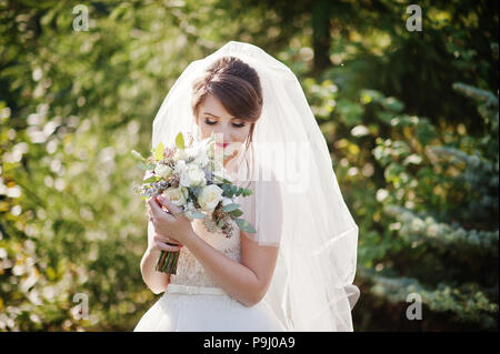 Portrait d'une douce superbe bride holding bouquet de mariage belle dans ses mains à l'extérieur. Banque D'Images