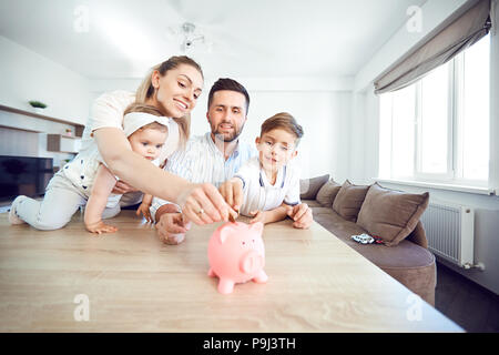 A smiling family fait économiser de l'argent avec une tirelire. Banque D'Images