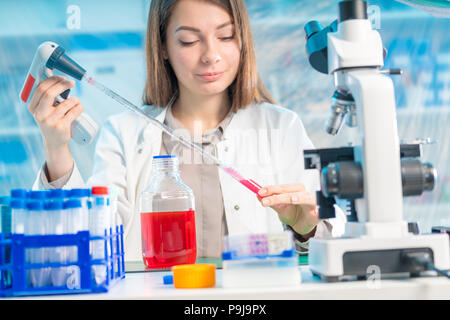 Jeune femme en laboratoire scientifique avec la pipette et produits chimiques dans les tubes à essai Banque D'Images