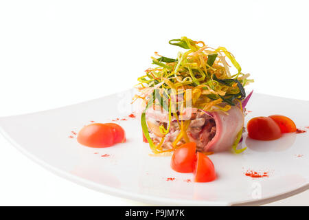 Salade avec du bacon, de la viande et des légumes, l'oignon et les tomates cerises sur une plaque blanche, isolée Banque D'Images