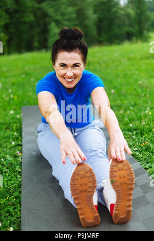 Happy Senior woman doing stretching exercises in park Banque D'Images