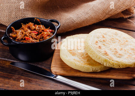 Petit-déjeuner vénézuelien, Arepas sur planche de bois et à côté un récipient avec de la viande pour remplir Banque D'Images