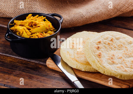 Petit-déjeuner vénézuelien, Arepas sur planche de bois et à côté un récipient avec du poulet pour remplir Banque D'Images