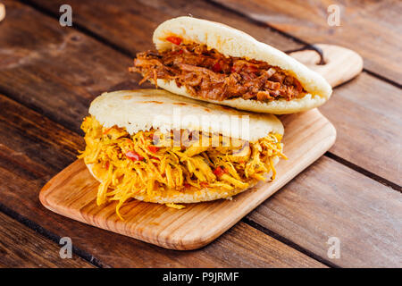 Petit-déjeuner sud-américain typique, arepa avec du poulet et de la viande rôtie sur planche de bois Banque D'Images