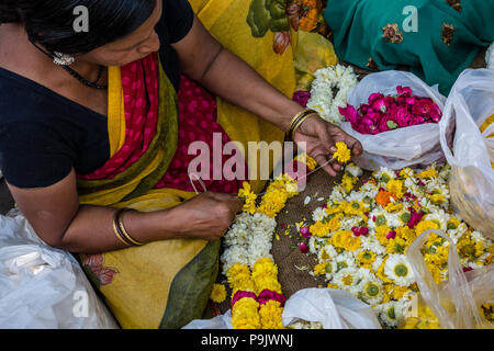 Femme indienne faisant des guirlandes de fleurs traditionnelles at a market stall dans Old Delhi, Delhi, Inde Banque D'Images