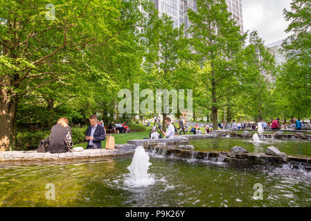 Les employés de bureau ayant leur pause déjeuner dans Jubilee Park, Canary Wharf, London, UK Banque D'Images