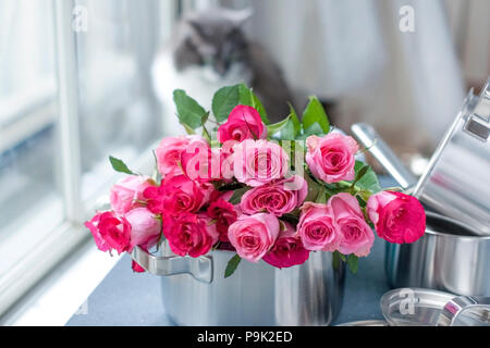 Un bouquet de roses fraîches, dans une casserole en acier, sur un fond noir en gris. Près de la fenêtre . Accueil chat. Place gratuite pour écrire du texte ou une carte postale Banque D'Images