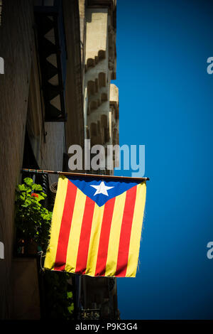 Drapeau de la catalogne contre le ciel bleu sur les rues de Barcelone Banque D'Images
