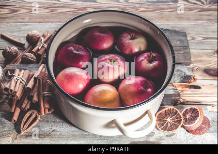 Pommes rouges bien mûrs dans une casserole pour vin chaud sur une table en bois. Banque D'Images