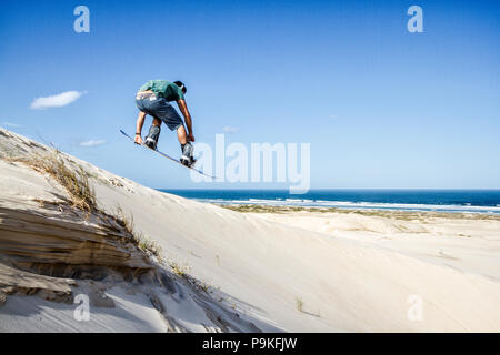 Sandboarder sautant une dune à Ribanceira Beach. Imbituba, Santa Catarina, Brésil. Banque D'Images