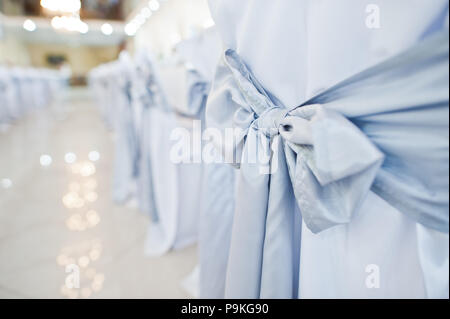 Photo en gros plan de big blue bows attachés sur des chaises de mariage blanc. Banque D'Images