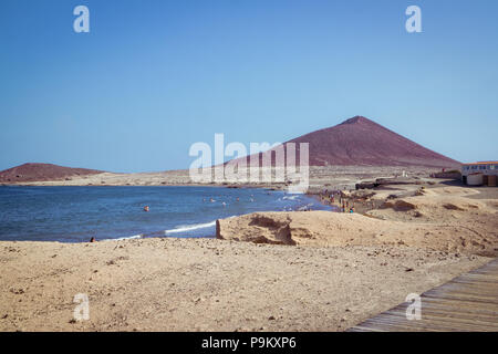 Playa El Médano beach et bay avec les touristes, l'océan Atlantique et la Montagne Rouge (La Montaña Roja) à Tenerife - Côte Sud Banque D'Images