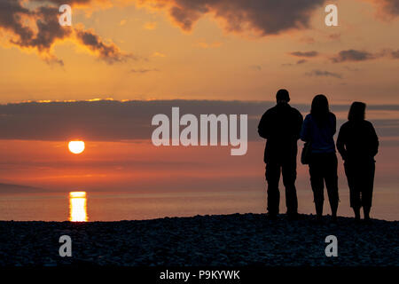 Penmon Point, Anglesey, Pays de Galles, le 18 juillet 2018. Météo France : à la fin d'une journée chaude sur l'Anglesey et ciel dégagé sur l'île, la journée se termine par un magnifique coucher de soleil avec une famille silhouetté contre le ciel firey - Crédit : DGDImages/Alamy Live News Banque D'Images