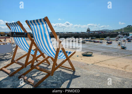 Un couple de chaises longues avec un signe réservé s'asseoir près de St Ives Smeaton's Pier et Port, St Ives, Cornwall, UK Banque D'Images