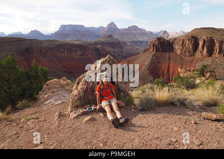 Jeune femme backpacker en faisant une pause pendant l'ascension de la nouvelle très éprouvantes Hance Trail dans le Parc National du Grand Canyon, Arizona, United States. Banque D'Images