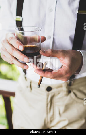 Homme tenant dans les mains un verre de whisky et de cigare Banque D'Images
