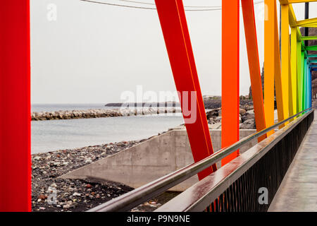 Un arc-en-ciel de couleurs vives contemporain Pont en treillis métallique sur une prise d'eau de mer à Ténérife. Banque D'Images