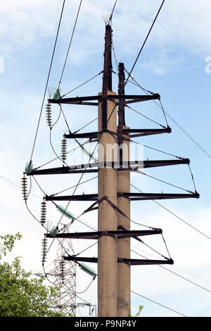 Poteaux en béton ronde avec isolateurs installés et les lignes haute tension contre le ciel bleu, close-up de la partie supérieure des structures Banque D'Images