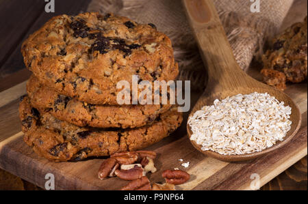 Libre d'une pile de cookies à l'avoine et aux raisins et des ingrédients sur une planche en bois Banque D'Images