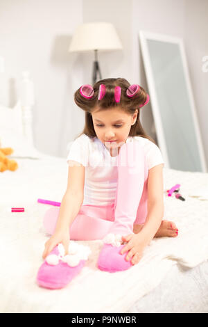 Cute girl putting chaussons sur. Banque D'Images