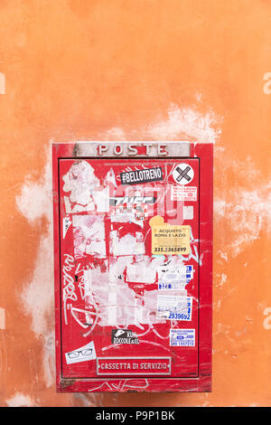 Une boîte aux lettres rouge orange sur un mur de plâtre, à Rome, Italie. Banque D'Images