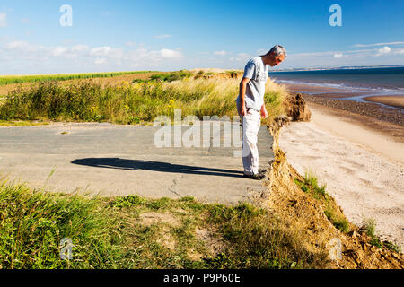 Une route côtière à près de Aldbrough sur la côte Est, près de Yorkshires Skipsea, UK. La côte est composé d'argiles, boulder doux très vulnérables à l'érosion côtière. Cette section de la côte, s'est érodée depuis l'époque romaine, avec de nombreux villages ayant disparu dans la mer, et est le plus rapide de la côte d'érosion en Europe. Le changement climatique est l'accélération de l'érosion, avec la montée du niveau de la mer, l'augmentation du temps orageux et augmenté les fortes pluies, qui jouent tous leur part. Banque D'Images